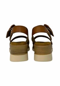 Sandali in pelle marrone con cinghie regolabili, soletta imbottita, tacco in legno e suola chiara. La vista posteriore mostra i dettagli delle cinghie.