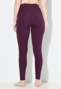 Leggings morados hechos de una tela elástica, con una cintura alta, ajuste slim y diseño hasta el tobillo. Textura suave sin patrones visibles.