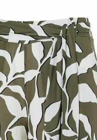 Green and white floral patterned fabric with a knotted waistband and pleats, featuring smooth texture and contrasting black outlines.