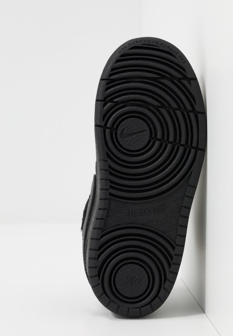 Semelle en caoutchouc noir avec des motifs de relief circulaires. Présente les inscriptions "NIKE" et "ALLDAY PLAY", conçue pour l'adhérence et la durabilité.