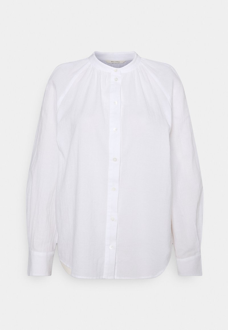 Blouse blanche à manches longues, boutons sur le devant, tissu froncé près du col, manches avec poignets.