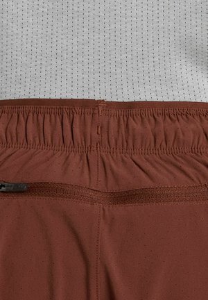 Pantaloncini bordeaux con vita elastica, caratterizzati da piccoli fori per la ventilazione e una texture del tessuto liscia.