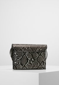 Bolso rectangular con estampado de piel de serpiente en negro y gris, con cierre de solapa, expuesto en un pedestal blanco contra un fondo liso.