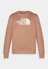 Sudadera marrón con cuello y puños acanalados. Presenta un gran logo blanco que dice "THE NORTH FACE" en la parte frontal. Material suave.