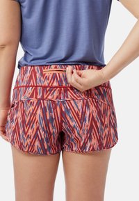Röda och rosa mönstrade shorts med en dragkedjeficka bak, matchade med en blå topp.Shortsen har en zickzackdesign och elastisk tyg.