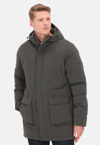 Geacă parka căptușită în gri închis, prevăzută cu glugă, două buzunare superioare cu fermoar și două buzunare frontale cu clape. Material neted și durabil, cu accente cusute.