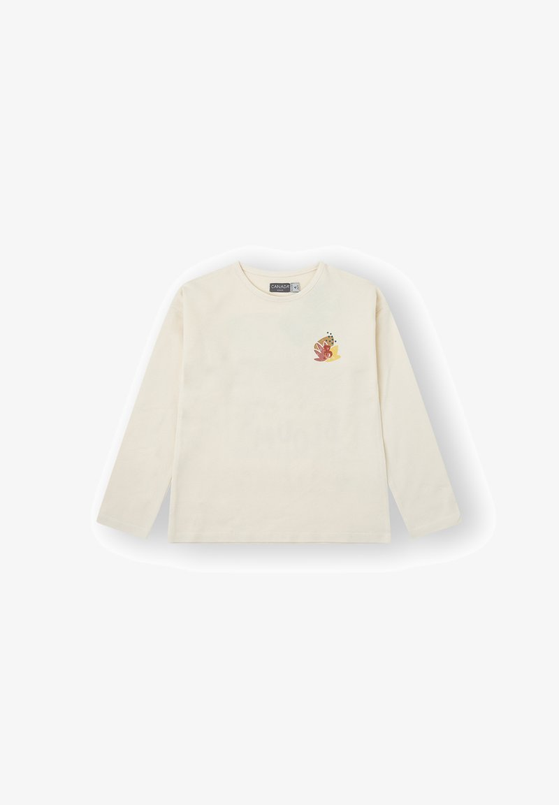 Camiseta de manga larga de color crema hecha de algodón, con un pequeño diseño floral colorido en el lado izquierdo del pecho.