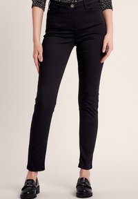 Zwarte slim fit broek van gladde stof, ontworpen met een middelhoge tailleband, vijf zakken en een knoopsluiting. Platte naden decoratie.