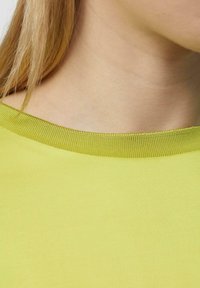 Limoengroene top met korte mouwen, voorzien van een ronde halslijn en ribbelkraag, gemaakt van gladde katoenen stof met een nette afwerking.
