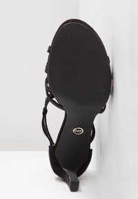 Sandale noire à talon haut avec motif ondulé sur la semelle, taille 37 et logo MT en métal sur le dessous.