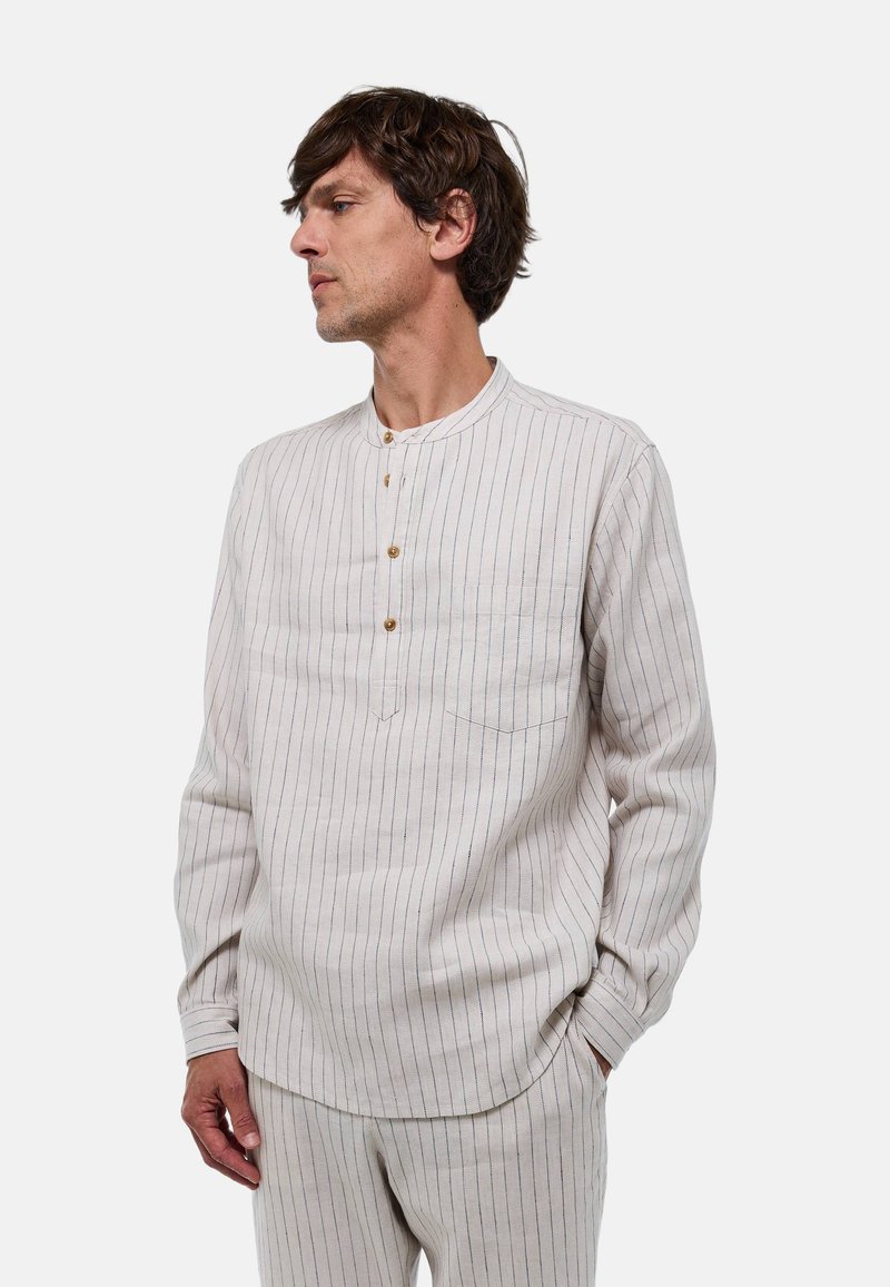 Chemise à manches longues rayée beige clair avec col mandarin, boutons en bois et poche poitrine. Fabriquée en tissu texturé.