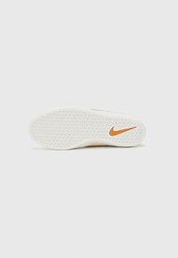 Sola de sneaker Nike, predominantemente branca com um padrão texturizado. Apresenta um logótipo Nike laranja, oferecendo um design limpo e funcional.