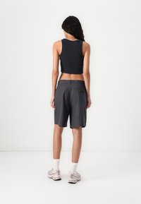 Black cropped tank top paired with gray and black checkered shorts, featuring a back pocket with a logo and a relaxed fit.