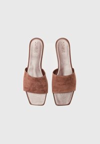Brune suedette glidesandaler med en bred strop, firkantet tådesign og en glat, let skinnende indersål. Branding synlig på indersålen.