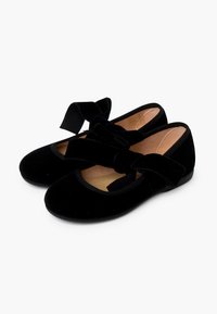 Bailarinas de terciopelo negro con punta redondeada, que presentan un gran lazo de tela en cada zapato y una plantilla texturizada. Suelas planas para mayor comodidad.