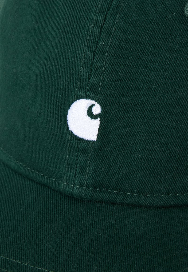 Cappellino da baseball verde scuro con un piccolo logo bianco ricamato sul pannello frontale vicino alla cucitura.