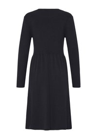 Robe noire à manches longues, longueur genoux, taille cintrée et jupe légèrement évasée, vue de dos sur fond blanc uni.