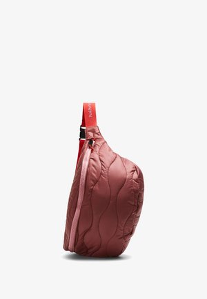 Sac bandoulière rouge matelassé avec fermeture éclair rose et bandoulière rouge ajustable comportant un texte blanc sur fond blanc.