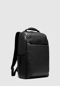 Mochila de cuero negro con acabado texturizado, que cuenta con un compartimento con cremallera y una asa superior. Incluye correas de hombro ajustables.