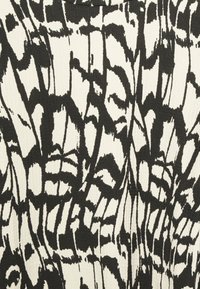 Schwarz-weißer Stoff mit einem abstrakten Blumenmuster. Die Textur wirkt gerippt und zeigt kräftige, geschwungene Linien und Formen.