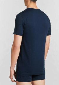 T-shirt in cotone blu navy con maniche corte e collo giro, abbinato a pantaloni boxer blu navy, che mostra una trama liscia in un design aderente.