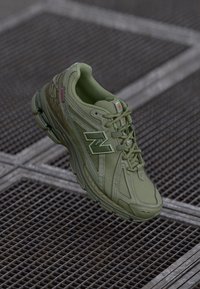 Baskets de sport vertes avec une maille respirante, un tissu texturé et une semelle rembourrée. Présente des accents réfléchissants et un logo bien en vue sur le côté.