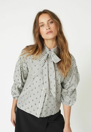 Button-up shirt with a bow tie collar, featuring vertical black and white stripes and small dotted patterns. Puff sleeves add volume.