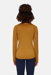 Maglietta sportiva a maniche lunghe in ambra con design senza cuciture, cuciture arancioni a contrasto e logo sul retro; texture liscia, forma aderente.