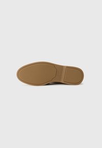Semelle de chaussure en caoutchouc brun avec une surface lisse, une forme arrondie, un détail de logo subtil et de légères rainures pour une meilleure adhérence.