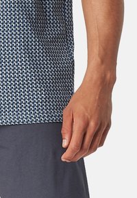 Korte mouwen shirt in blauwwit geometrisch patroon. Lichtgewicht stof met een soepele textuur, gecombineerd met donkerblauwe broek.