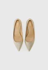Zlaté trblietavé lodičky s ostrými špičkami a hladkým béžovým koženým interiérom. Majú klasický dizajn s nízkym výrezom.
