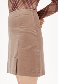 Brauner Cordrock mit gerader Silhouette, Seitenreißverschluss und einem kleinen Schlitz am Saum. Verfügt über eine vertikale Rippstruktur und ein Etikett an der Seite.