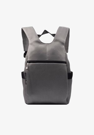 Mochila de malla gris con correas acolchadas, bolsillo frontal con cremallera y bolsillos laterales. Superficie texturizada con una forma rectangular moderna.