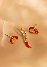 Boucles d'oreilles dorées avec des accents en émail rouge, au design incurvé en forme de crevette et un pendentif en forme de piment.