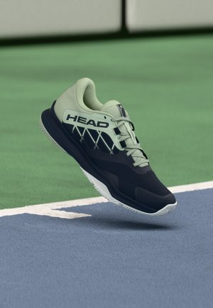 Zapatilla deportiva en azul marino oscuro y verde claro. Parte superior de malla con superficie texturizada, acentos contrastantes y suela exterior blanca diseñada para ofrecer tracción.