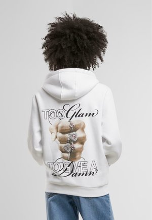 Sweatshirt blanc mettant en avant un graphique d'un poing fermé orné de bagues, avec le texte "Trop Glam pour s'en soucier", agrémenté de accents noirs.