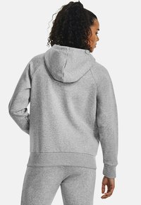 Szara bluza z kapturem, wykonana z miękkiego materiału, z regulowanym kapturem, ściągaczami przy mankietach i u dołu. Casualowy design z rękawami raglanowymi, noszona z pasującymi spodniami.
