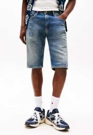 Blå denimshorts med en afslappet pasform, der har forlommer og en falmet tekstur. Bruges med hvide sokker og marineblå sneakers.