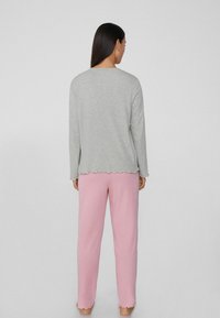 Top gris de manga larga con dobladillo en forma de ola, combinado con pantalones rosados. Ambas prendas cuentan con una textura suave y un ajuste relajado.