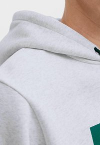 Lys grå hoodie med en blød tekstur, prydet med snor i mørkegrøn, der viser en del af hætten og skulderområdet.