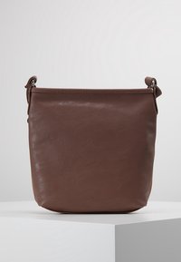 Braune Leder-Eimerhandtasche mit glatter Textur, minimalistischen Design und einem abnehmbaren Schultergurt. Verfügt über Hardware-Akzente in Silber.