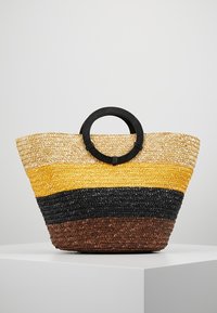 Woven straw bag with a circular black handle, featuring horizontal stripes of natural, yellow, black, and brown colors. Textured, spacious design.