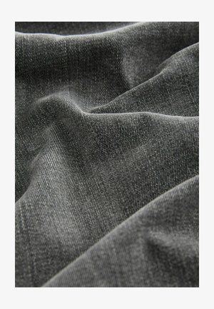 Tejido de mezclilla gris oscuro con una superficie texturada, que presenta patrones de tejido visibles y suaves pliegues, mostrando un acabado suave y ligeramente brillante.