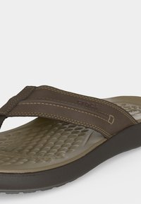 Καφέ σανδάλι Crocs με υφή στο πέλμα, μαλακό επενδεδυμένο λουράκι και ανθεκτική σόλα, σχεδιασμένο για άνεση και καθημερινή χρήση.