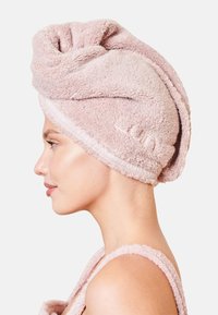 Ljusrosa, mjuk och absorberande frottéhårhandduk med en tvinnad design, texturerad yta och ett elastiskt band med varumärkeslogotyp. Mjukt och absorberande material.