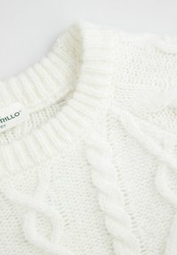 Biały sweter z dzianiny z ribbowanym okrągłym dekoltem, wzorem w warkocze i miękką teksturą. Etykieta widoczna wewnątrz.