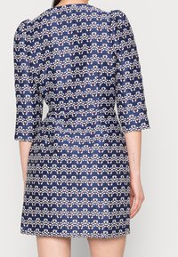 Krótkosleeve, dopasowana sukienka w kolorze granatowym z białym i czerwonym wzorem w zygzak, posiadająca teksturowany materiał i subtelne bufiaste rękawy.
