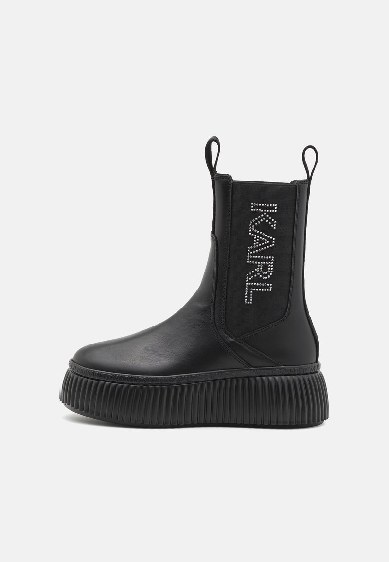 Bottes chelsea noires en cuir lisse avec des panneaux latéraux élastiques, une semelle plateforme striée, et ornées du nom "KARL" en strass.
