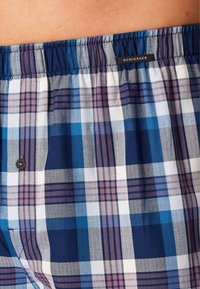 Boxers à carreaux pour homme en bleu, blanc et violet, avec un motif de type quilt, une taille élastique et une petite étiquette de marque cousue.