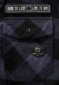 Camicia a quadri nera e viola con etichetta ricamata e spilla a forma di teschio argentato sulla tasca, realizzata in tessuto testurizzato con chiusura a bottoni.
